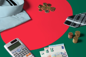 Bangladesh flag on minimal money concept table. Coins and financial objects on flag surface. National economy theme.