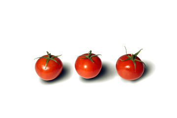 Isolated objects. Red fresh juicy tomatoes in front of a white background. Three objects are arranged in a row. Different angle.