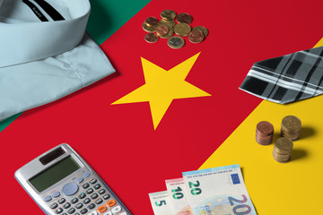 Cameroon flag on minimal money concept table. Coins and financial objects on flag surface. National economy theme.