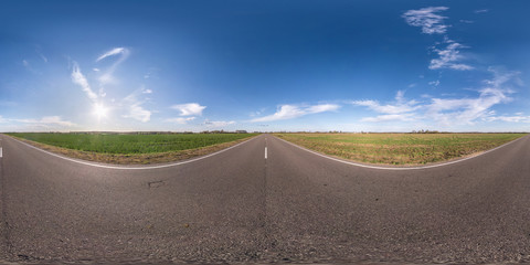 Full spherical seamless panorama 360 degrees angle view on no traffic asphalt road among fields in evening  before sunset with cloudy sky. 360 panorama in equirectangular projection, VR AR content