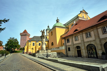 Fototapeta na wymiar cobbled street with a statue of lancer and a historic church and a tower of a medieval castle in Poznan.