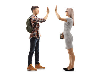 Young female teacher holding books and gesturing high-five with a male student