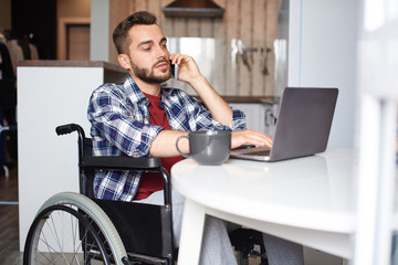 Disabled man with smart phone and laptop