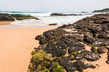 Fototapeta na wymiar Waves Crash Over Exposed Coral Reef With Kilauea Lighthouse in The Distance, Kauapea Beach (Secret Beach), Kauai, Hawaii, USA
