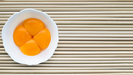 Yellow egg yolks in a white cup.