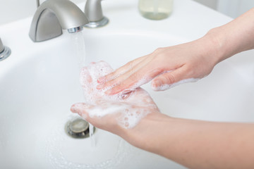 Person washing their hands at with soap and water for coronavirus prevention