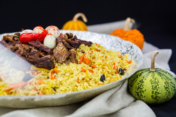 Pilaf and ingredients on plate with oriental ornament on a black background. Central-Asian cuisine - Plov Top view