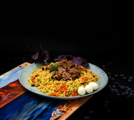 Pilaf and ingredients on plate with oriental ornament on a black background. Central-Asian cuisine - Plov Top view