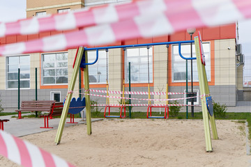 Swing for children and Tape barrier in a closed playground during the period of quarantine and...