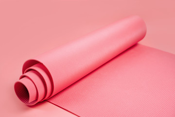 Rolled yoga mat on pink  background.  Equipment for yoga and meditation. Healthy lifestyle concept.  Home  workout.