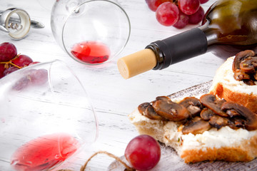 Obraz na płótnie Canvas 2 glasses of red wine, , bottle , grapes, corkscrew, snacks with cheese and mushrooms on a white wooden