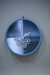 Modern art spin on the wall watch. Blue wall clock with second hand hanging on the wall. Minimalist flat lay image of plastic wall clock over blue turquiose background with copy space