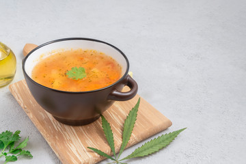 Bowl of homemade cannabis soup on light concrete background with space for text