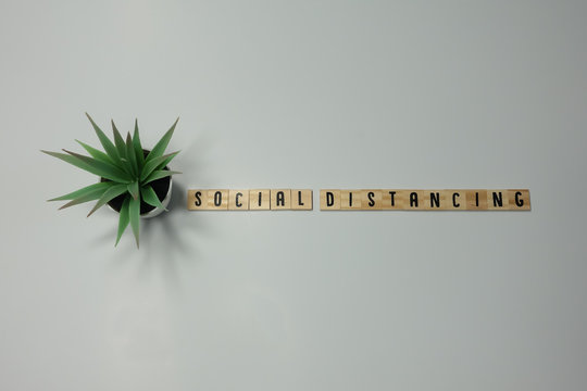 The word Social Distancing written in wooden letter tiles on a white background. - Powered by Adobe