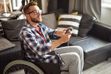 Disabled man in wheelchair playing video games at home