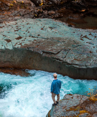 Man standing on rock over raging river in Mt. Rainier National park