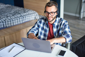 Disabled man using laptop and headset at home