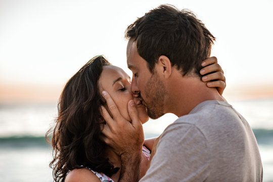 Loving couple sharing a kiss on a beach at dusk
