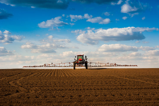 Self-propelled Sprayer With Long Arms, Fertilizer Spreader That Fertilizes Farm Fields View With Beautiful Clouds.