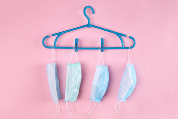 fashion outfit at pandemic time. face masks hanging on a rack over pastel pink background.