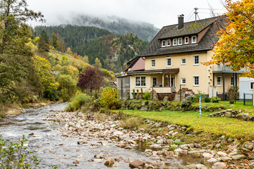 Fototapeta na wymiar River and houses in a rainy day in Schönmünzach