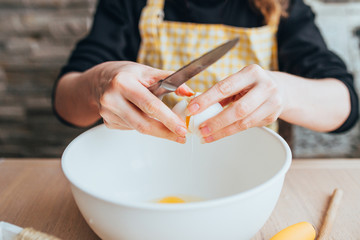 Obraz na płótnie Canvas Charlotte apple pie baking - Woman adds raw chicken eggs to a bowl with dough