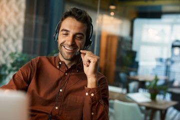 Smiling businessman talking on a headset while working late