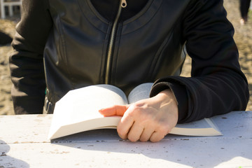 Young lonely woman sitting on chair, reading book on wooden table. Relaxation, cultural activity...