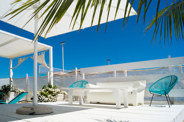 Sunny beach with palm tree and white and blue beach furniture, in Italy