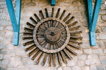 The wheel of a water mill. The old wooden wheel of the water mill is used as an element of decor on the wall.