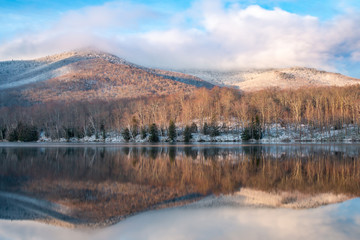 A dramatic reflection of mountains in an Adirondack lake after a spring snow storm.  - 343245085