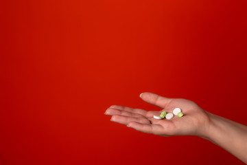 On the palm of the girl are tablets of green and white. The photo was taken on an orange background in a photo studio. Medical pills.