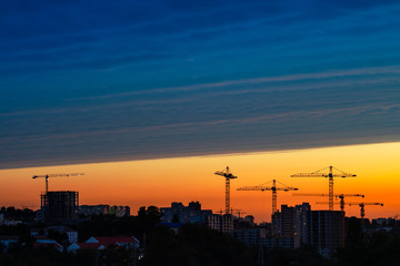 Evening blue hour Kiev city view with unfinished buildings and construction cranes 