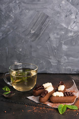 Chocolate rum balls with green mint tea on dark background. Brown sweets with cream