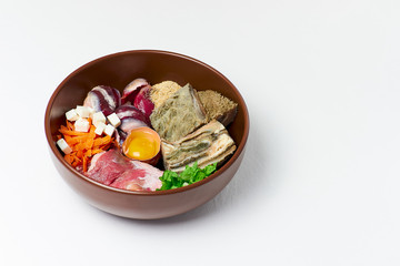 Different natural raw dog food BARF diet in bowl on white background Meat organs egg vegetables organic food supplements
