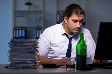 Alcohol addicted businessman working late in the office