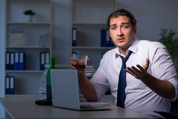 Alcohol addicted businessman working late in the office