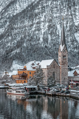 Snowy village Hallstatt by lake at foot of snow mountain with clear sky in winter in Austria