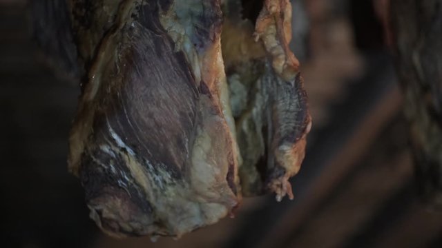Smoked ham hangs in the dark attic