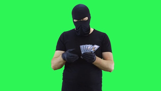 A masked man holds money in his hands, counts it and throws it down.Balaclava.Green screen background.