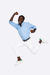 Smiling handsome african man in casual clothes celebrates victory, jumps and shows a flurry of emotions  on isolated white background