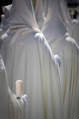 Detail penitent white holding a candle during Holy Week, Spain