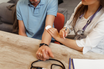 Cropped image, female doctor injecting senior male patient with syringe
