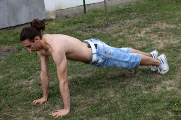 Handsome caucasian guy is working out in the nature.  Gymnastics, healthy lifestyle concept.
