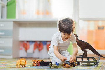 Cute little kid boy playing with lots of toy cars indoor. Happy preschooler having fun at home or nursery. Big collection of different vehicles. Happiness game.