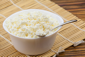 Tasty fresh grained cottage cheese on a plate on  wooden table