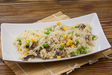 Tasty appetizing risotto on  white plate on  wooden background