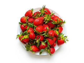 White plate full of red juicy strawberries, top view