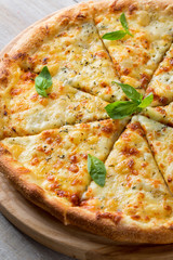 Pizza four cheeses on bamboo bottom on wooden table