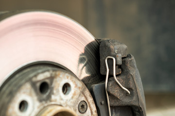 Closeup of braking disc of the vehicle with brake caliper for repair in process of new tire...